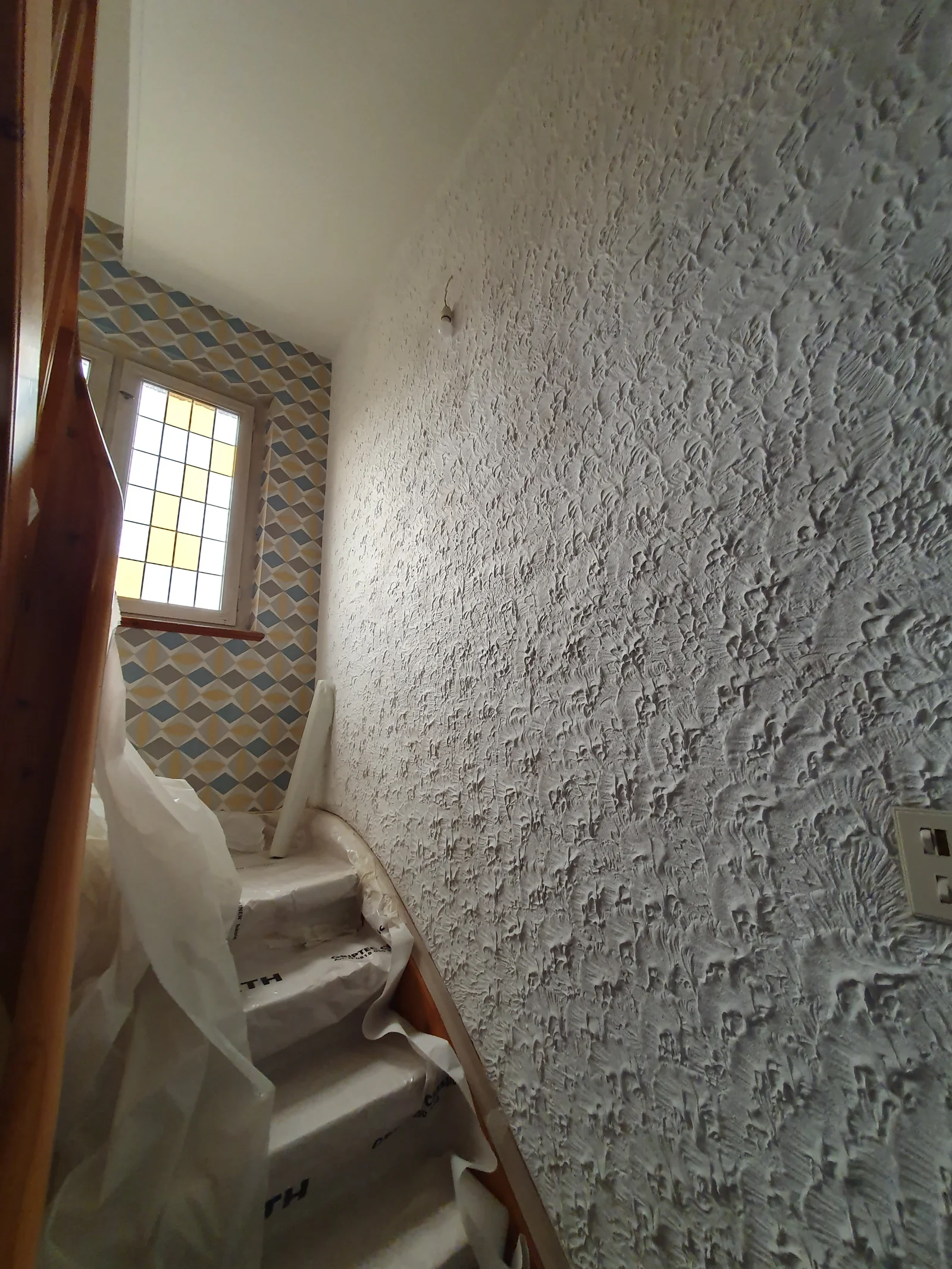 Cage d'escalier avant travaux avec vieux papier peint sombre